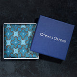 Tile design silk pocket square in navy, turquoise and brown folded neatly in Otway & Orford branded blue gift box.