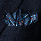 'Cypress' paisley silk pocket square in red and blue by Otway & Orford folded with points showing in top pocket of blue jacket.