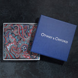 Paisley pattern silk pocket square in red and blue neatly folded in its Otway & Orford branded blue gift box.