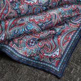 Close up of paisley pattern silk pocket square in red and blue by Otway & Orford gently folded.