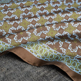 Close up of tile design silk pocket square in brown, green and turquoise by Otway & Orford folded gently.