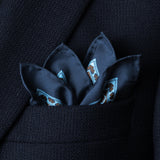 Tile design silk pocket square in navy, turquoise and brown by Otway & Orford folded with points showing in top pocket of blue jacket.