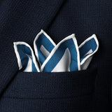 Watch dial design silk pocket square with white background and blue and grey watch dials folded with points showing in top pocket of navy blue jacket.