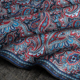 Close up of paisley pattern silk pocket square in red and blue by Otway & Orford gently folded.