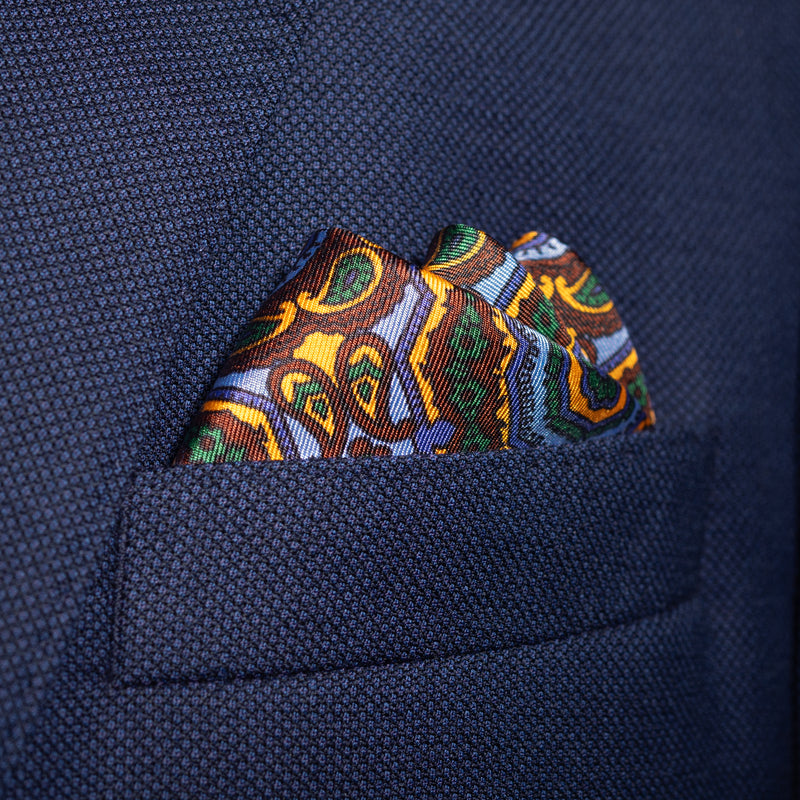 Whirligig medallion silk pocket square in blue, orange, brown & green by Otway & Orford folded in top pocket