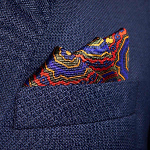 Whirligig medallion silk pocket square in red, green, blue & gold by Otway & Orford folded in top pocket