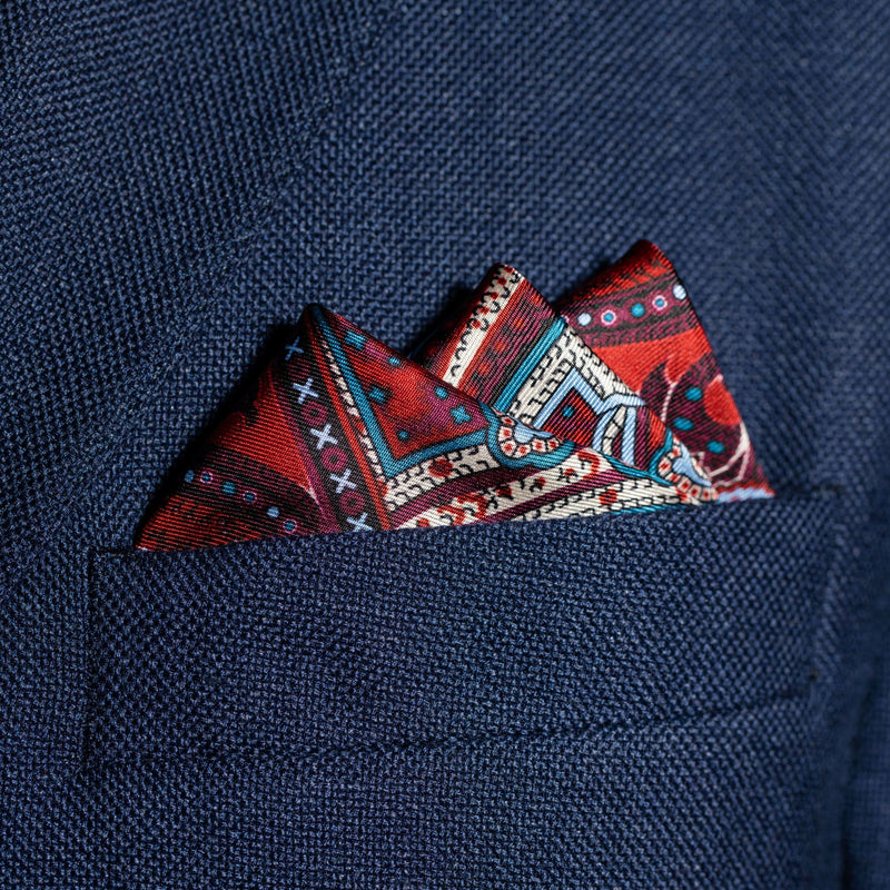 Intricate paisley design silk pocket square in burgundy, red, blue & cream by Otway & Orford folded in top pocket