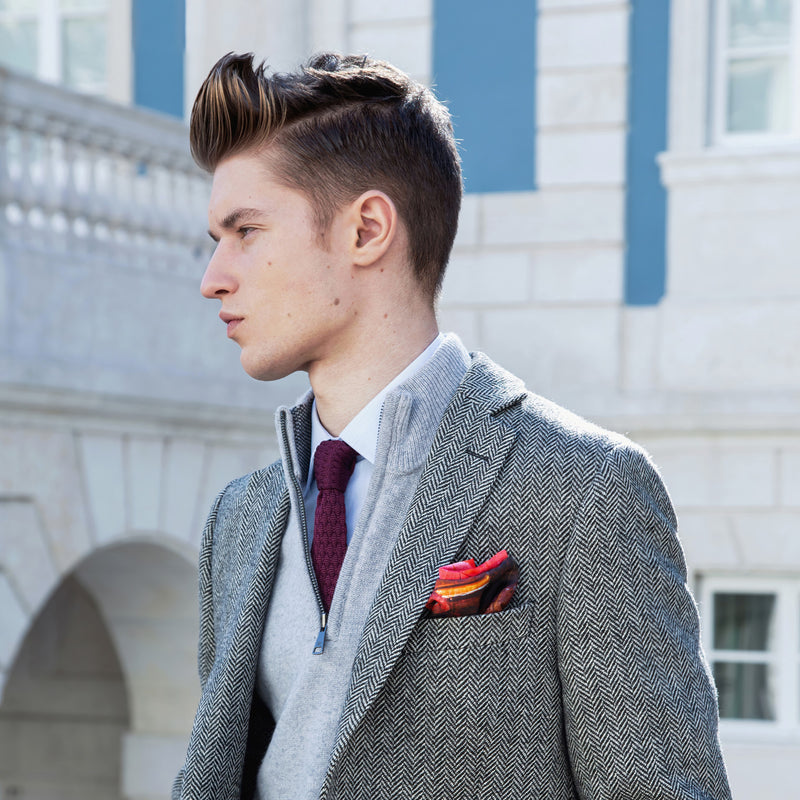 Classic German sports car inspired silk pocket square in red, yellow and blue by Otway & Orford on model worn with grey herringbone tweed jacket